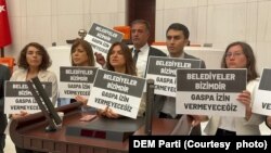 DEM Partili Hakkari Milletvekili Vezir Coşkun Parlak'ın konuşmasının bitiminde DEM Parti vekilleri, “Belediyeler bizimdir, gaspa izin vermeyeceğiz” yazılı dövizlerle kürsü işgali eylemi düzenledi.