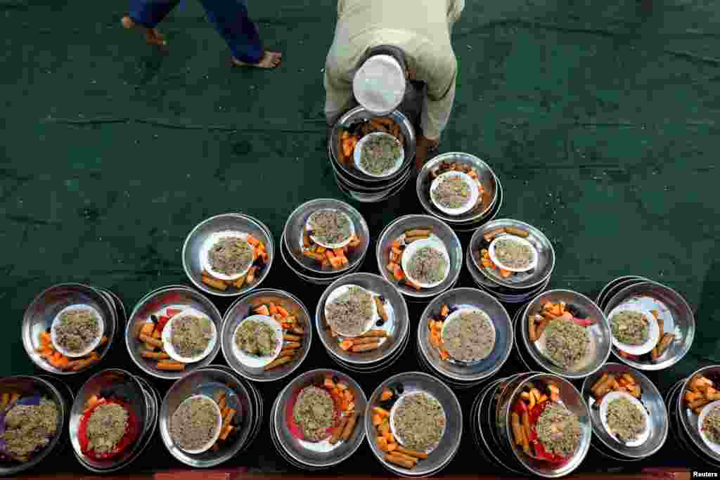 Pakistan&rsquo;ın Karaçi kentinde bulunan bir camiide iftarını açan cemaate bir gönüllü yiyecek dağıtıyor.