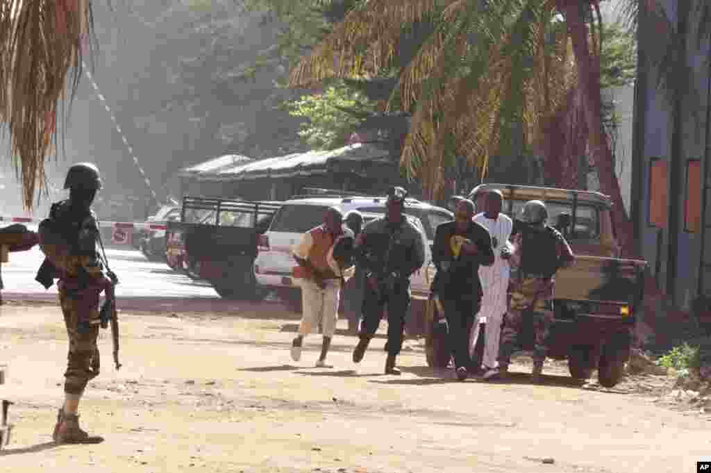 People run to flee from the Radisson Blu Hotel in Bamako, Mali, Friday, Nov. 20, 2015.